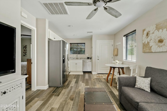 living room with hardwood / wood-style flooring, ceiling fan, and sink