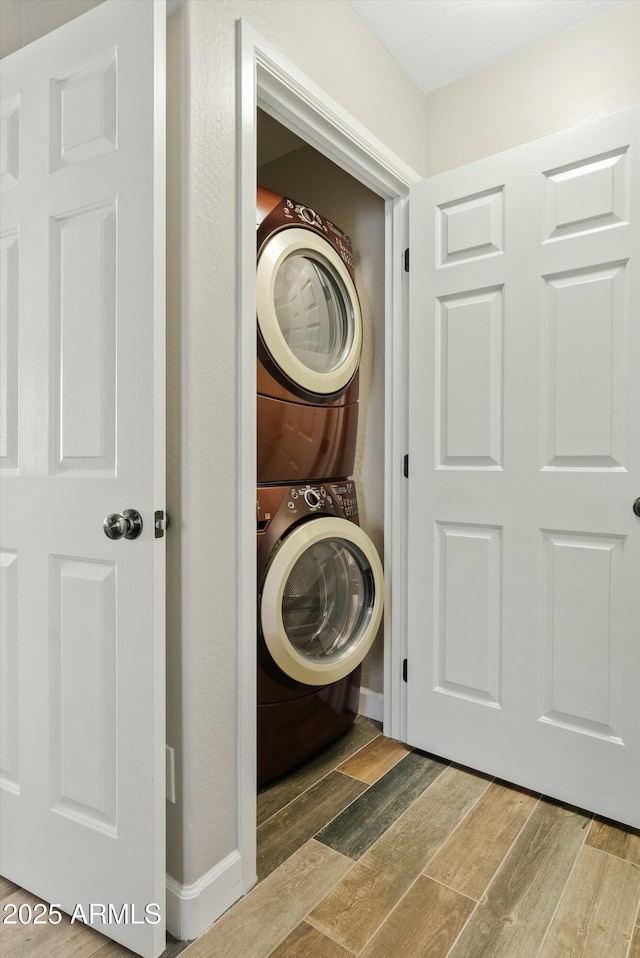 laundry area featuring stacked washer and clothes dryer and hardwood / wood-style floors