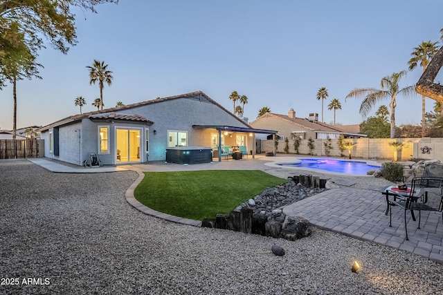 back house at dusk with a pool with hot tub, cooling unit, and a patio area