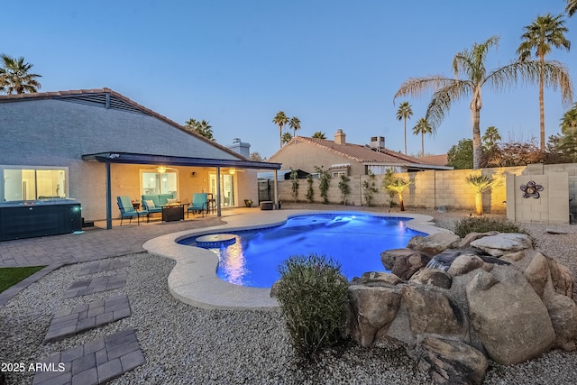 pool at dusk featuring outdoor lounge area, a patio area, and a hot tub