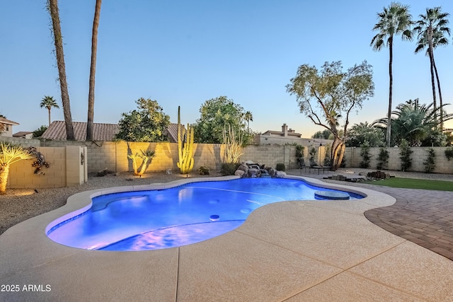 pool at dusk featuring a patio area