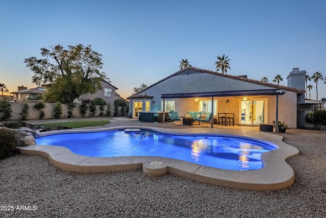 pool at dusk with an outdoor living space and a patio