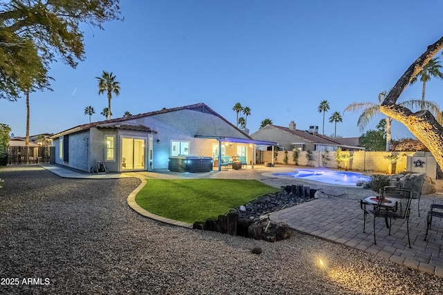 back house at dusk with a swimming pool with hot tub and a patio