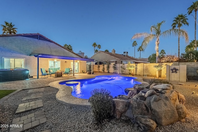 pool at dusk with outdoor lounge area, a jacuzzi, and a patio area