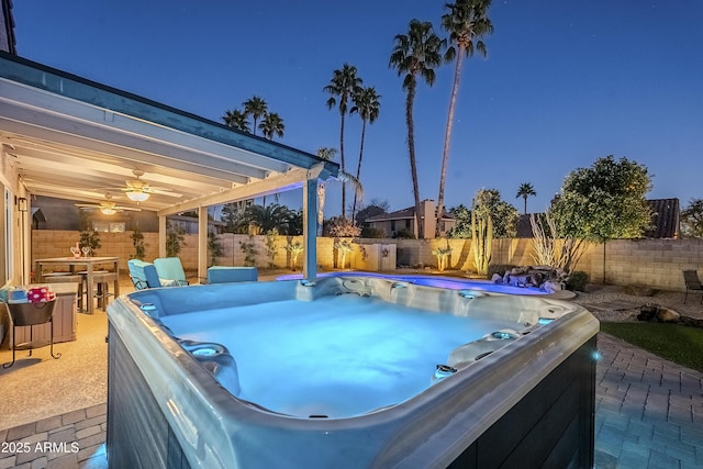 pool at dusk with ceiling fan and a patio