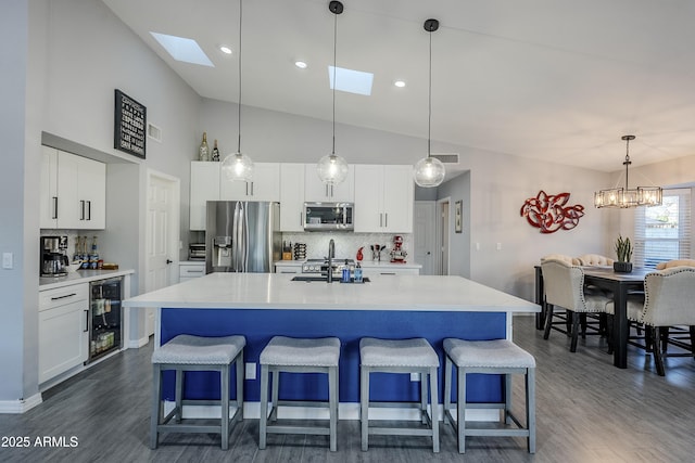 kitchen featuring stainless steel appliances, hanging light fixtures, a kitchen island with sink, and white cabinets