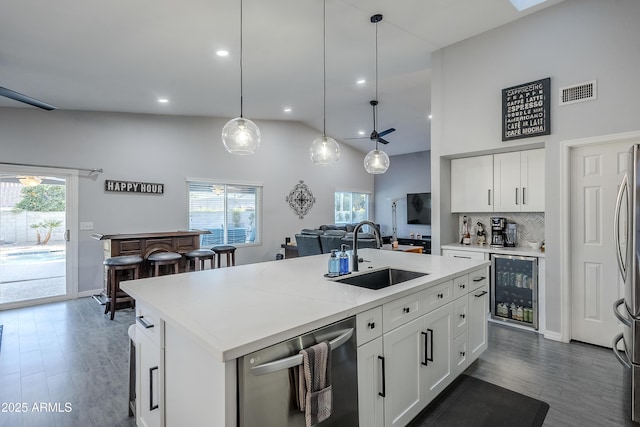 kitchen featuring sink, white cabinetry, a center island with sink, dishwasher, and beverage cooler