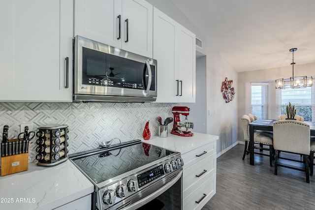 kitchen with lofted ceiling, light stone counters, tasteful backsplash, appliances with stainless steel finishes, and white cabinets