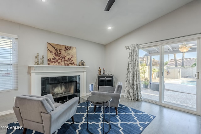 living room featuring vaulted ceiling, hardwood / wood-style floors, ceiling fan, and a fireplace