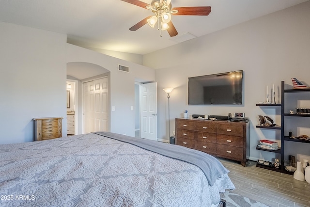 bedroom featuring lofted ceiling, ensuite bath, light hardwood / wood-style flooring, and ceiling fan