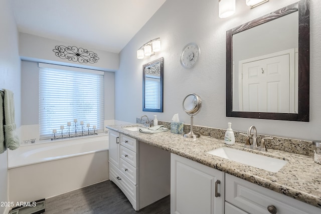 bathroom with hardwood / wood-style flooring, vanity, lofted ceiling, and a bathtub