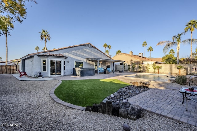 rear view of house with a hot tub and a patio