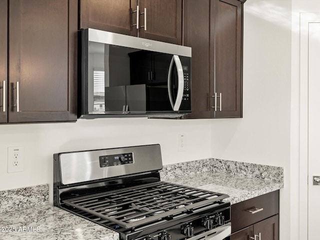 kitchen with dark brown cabinetry, light stone countertops, and appliances with stainless steel finishes