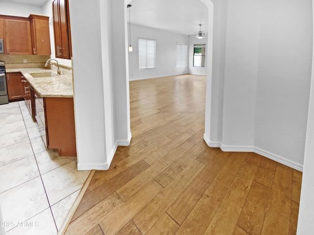 corridor with a sink, light wood finished floors, and baseboards