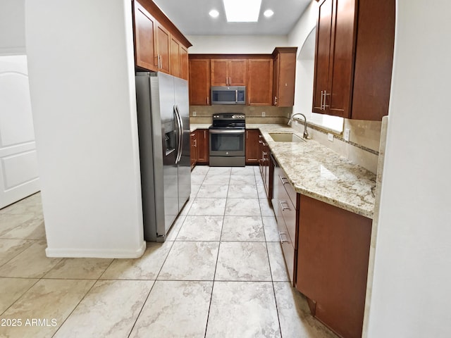 kitchen with appliances with stainless steel finishes, a sink, light stone counters, light marble finish floors, and recessed lighting