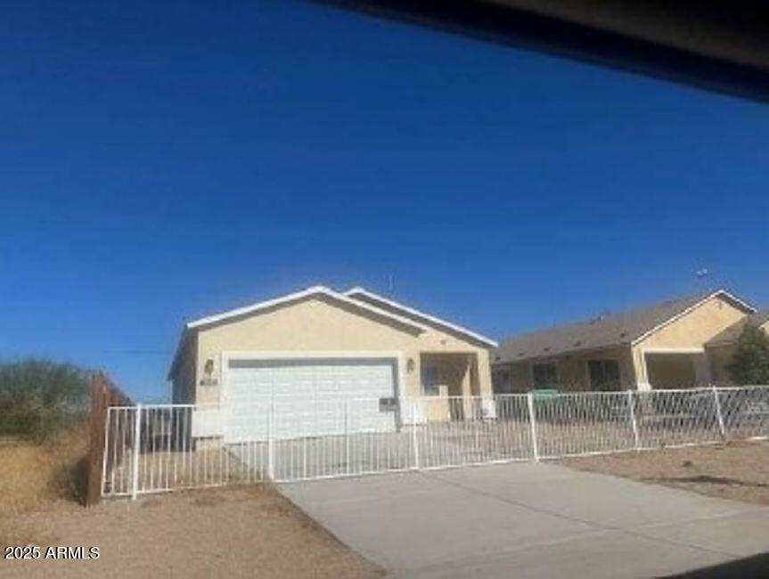 single story home featuring a garage, driveway, and fence