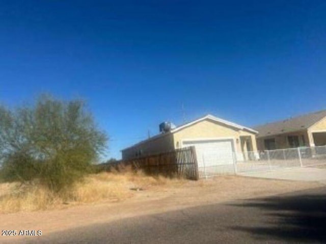 view of side of home with an attached garage, driveway, and fence