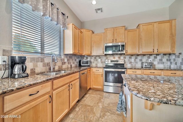 kitchen featuring stone countertops, sink, tasteful backsplash, and appliances with stainless steel finishes