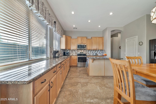 kitchen with decorative backsplash, a kitchen island, dark stone counters, and appliances with stainless steel finishes