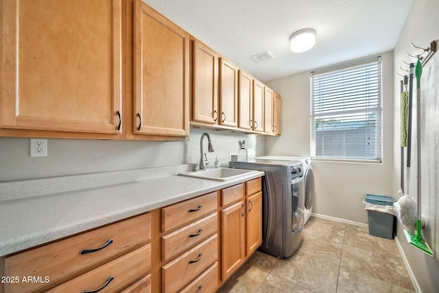 clothes washing area with cabinets, washer and clothes dryer, and sink