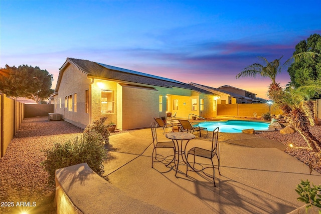 pool at dusk with a patio and central air condition unit