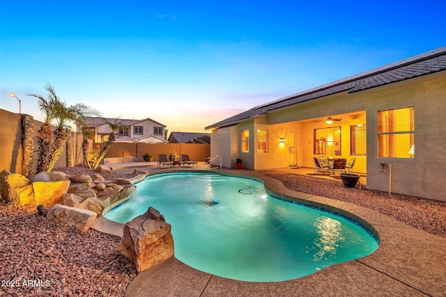 pool at dusk featuring a patio area and ceiling fan