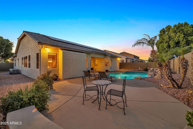 pool at dusk featuring central AC unit and a patio