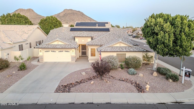 view of front facade with a garage, a mountain view, and solar panels