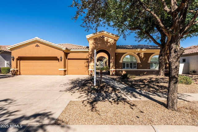 mediterranean / spanish home with concrete driveway, a tiled roof, an attached garage, and stucco siding