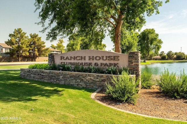 community sign with a yard and a water view