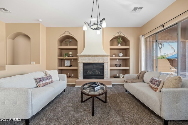 living room with built in features, dark colored carpet, a large fireplace, and visible vents