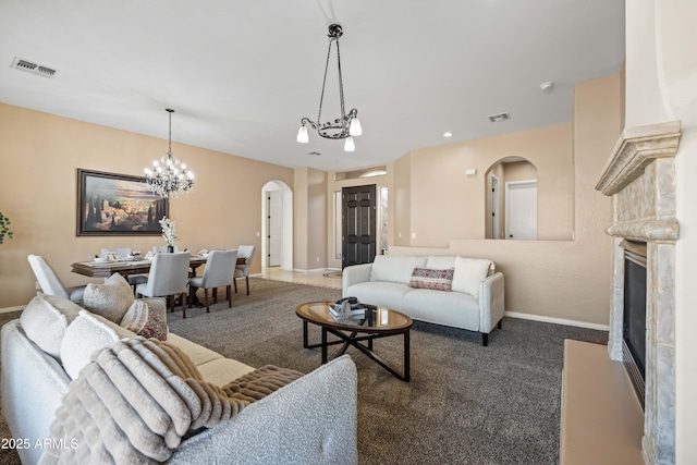 living area with dark carpet, a premium fireplace, visible vents, and arched walkways