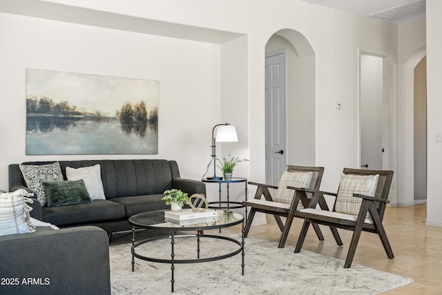 living room featuring light tile patterned floors, baseboards, and arched walkways