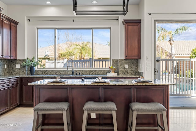 kitchen featuring tasteful backsplash, light stone counters, a breakfast bar, and a sink