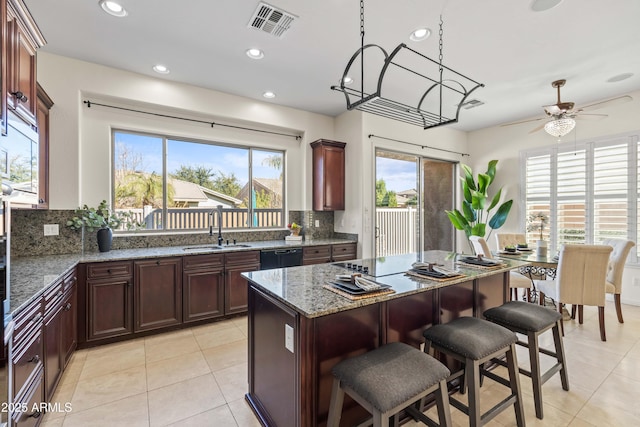 kitchen featuring light stone counters, visible vents, decorative backsplash, a sink, and black appliances