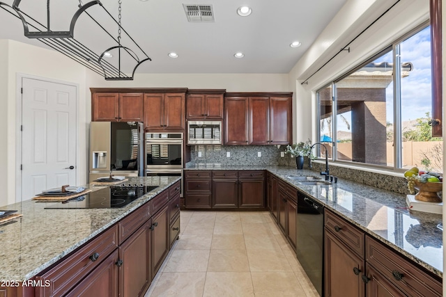 kitchen featuring visible vents, decorative backsplash, light stone countertops, black appliances, and a sink