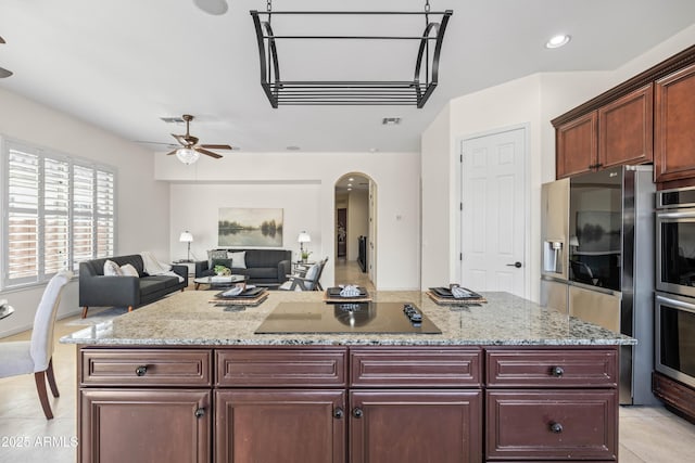 kitchen featuring arched walkways, open floor plan, stainless steel appliances, dark brown cabinets, and light tile patterned flooring