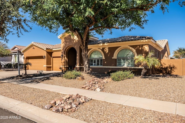 view of front facade with stucco siding, fence, a garage, driveway, and a tiled roof