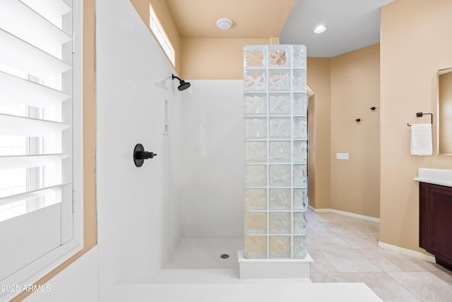 bathroom with baseboards, walk in shower, vanity, and tile patterned floors