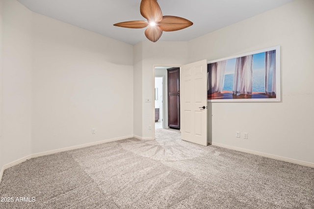 spare room featuring a ceiling fan, light carpet, and baseboards