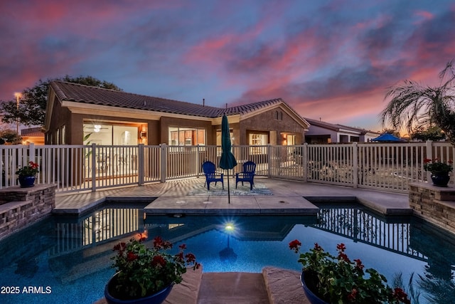 pool at dusk with a fenced in pool, fence, and a patio