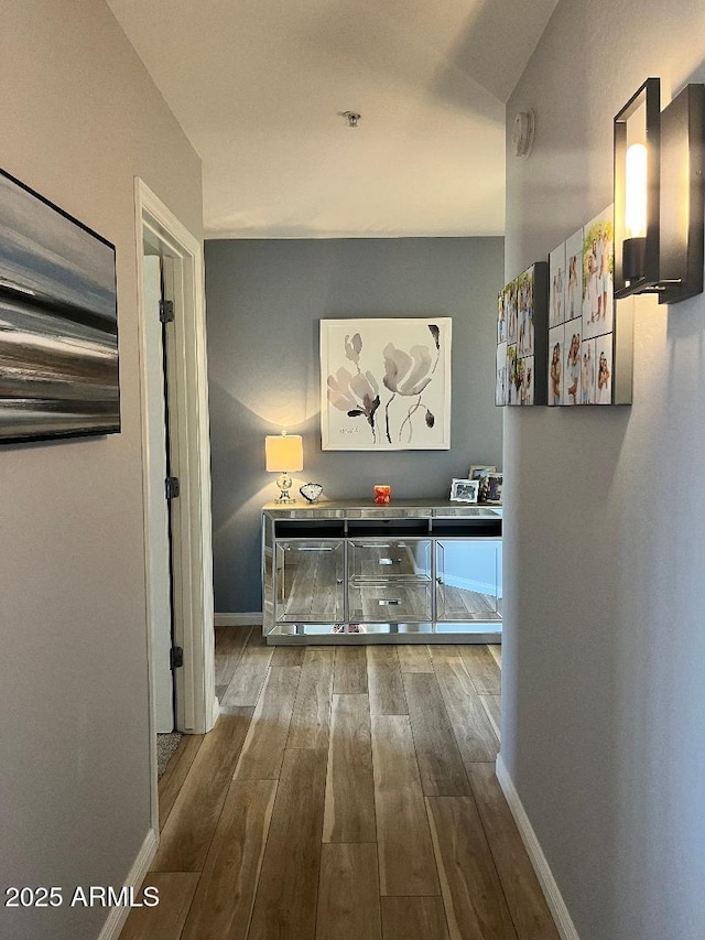 corridor with baseboards and wood finished floors