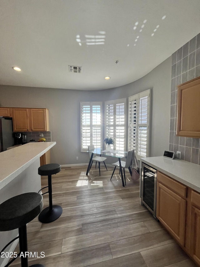kitchen with visible vents, freestanding refrigerator, decorative backsplash, wine cooler, and recessed lighting
