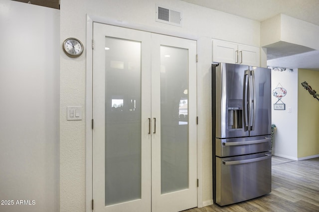 kitchen featuring white cabinetry, stainless steel fridge, and light wood-type flooring