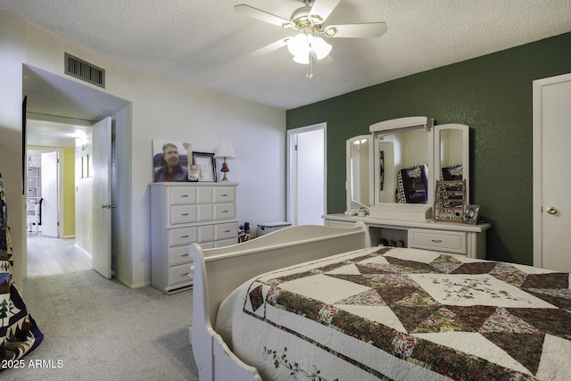 carpeted bedroom featuring ceiling fan and a textured ceiling