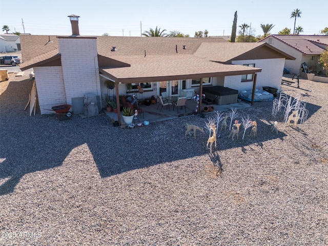 rear view of house with a patio area and a hot tub