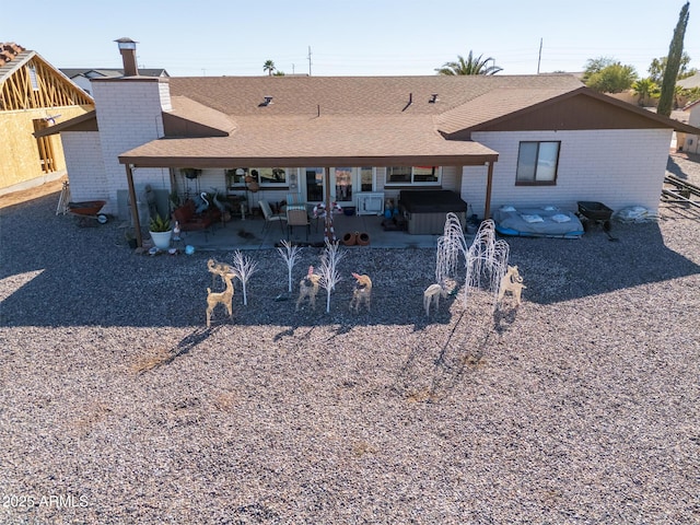 rear view of house featuring a patio and a hot tub