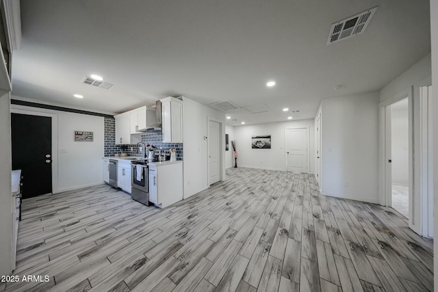 kitchen with appliances with stainless steel finishes, sink, white cabinets, backsplash, and light hardwood / wood-style floors