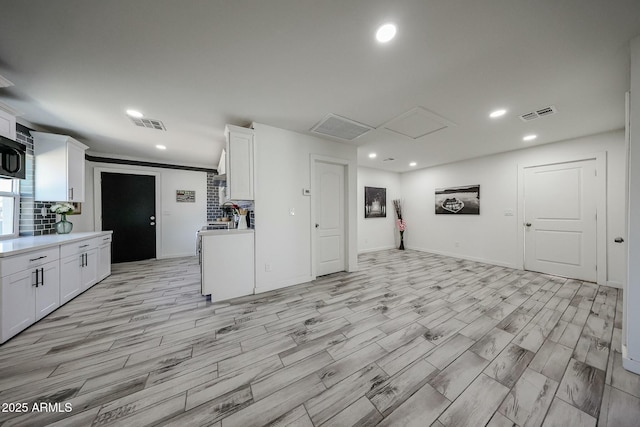 kitchen with backsplash, light hardwood / wood-style floors, and white cabinets