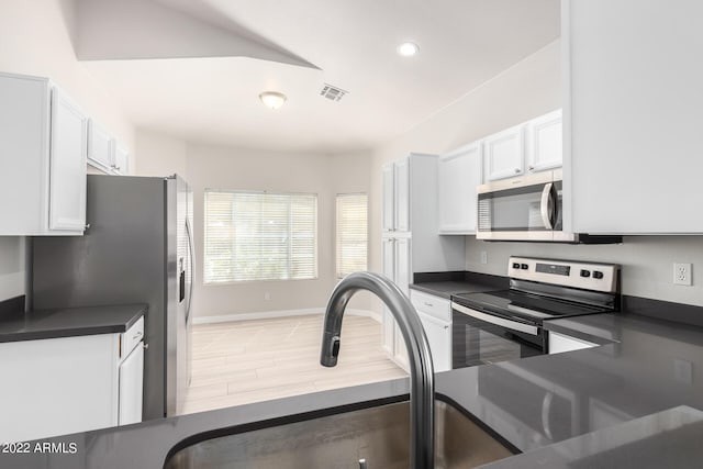 kitchen with hardwood / wood-style flooring, white cabinetry, and stainless steel appliances